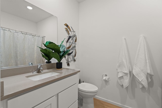 bathroom featuring toilet, recessed lighting, wood finished floors, vanity, and baseboards