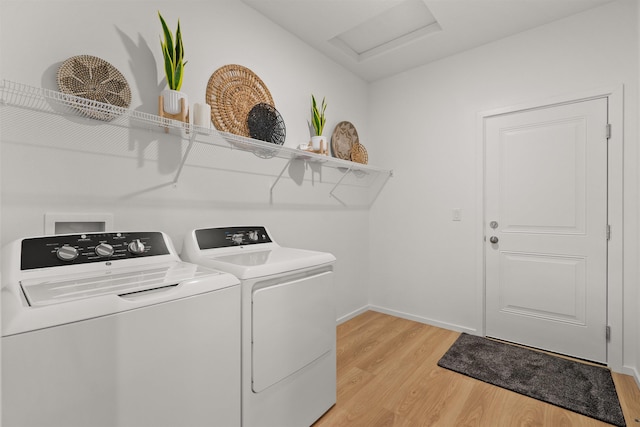 clothes washing area featuring attic access, washing machine and dryer, light wood-type flooring, laundry area, and baseboards