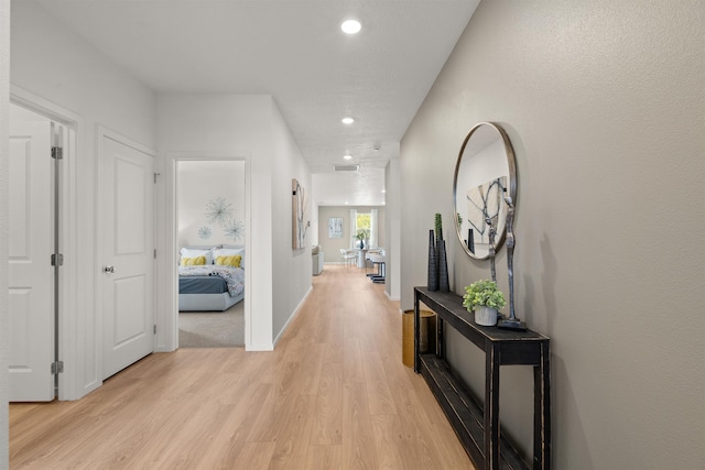 corridor featuring light wood-style floors, recessed lighting, visible vents, and baseboards