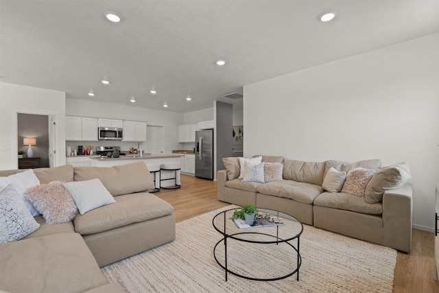 living room featuring light wood-type flooring, visible vents, and recessed lighting