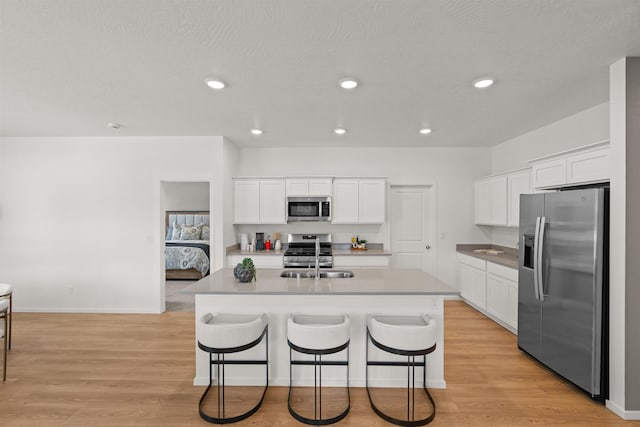 kitchen featuring appliances with stainless steel finishes, white cabinetry, and a sink