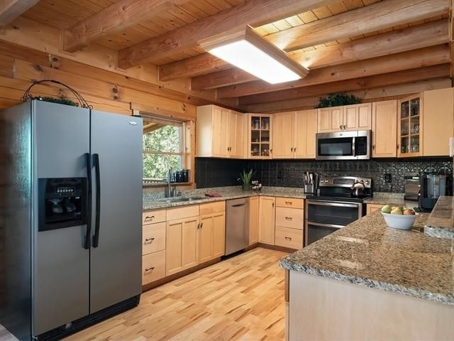 kitchen featuring light brown cabinets, sink, light hardwood / wood-style floors, light stone counters, and stainless steel appliances