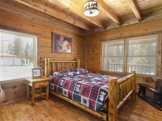 bedroom with beamed ceiling, hardwood / wood-style floors, wood walls, and wood ceiling