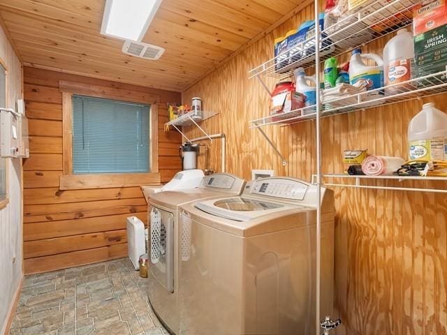 washroom featuring separate washer and dryer, wooden ceiling, and wood walls