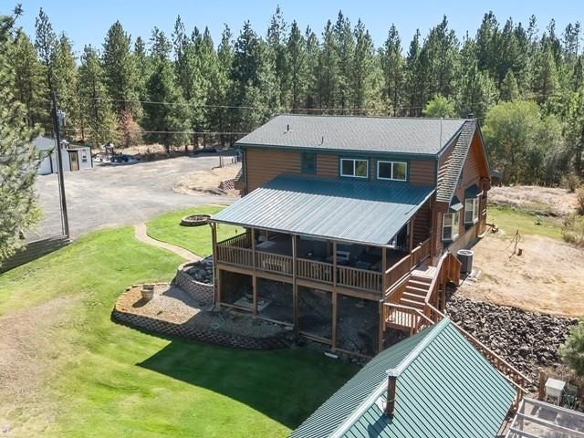 back of property with a yard, central AC unit, and a deck