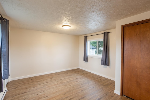 unfurnished bedroom with a textured ceiling, light hardwood / wood-style floors, and a baseboard radiator