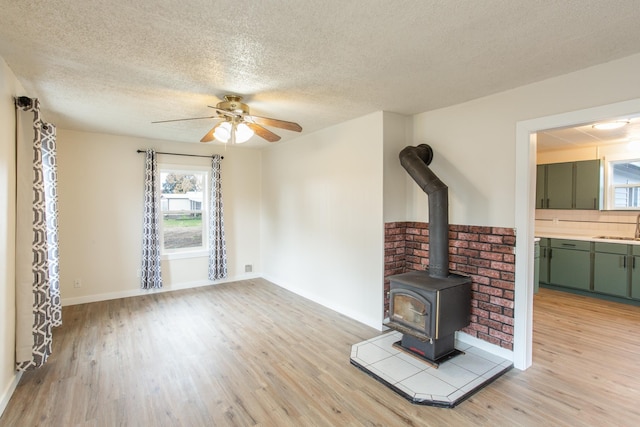 unfurnished living room with a textured ceiling, ceiling fan, light wood-type flooring, and sink