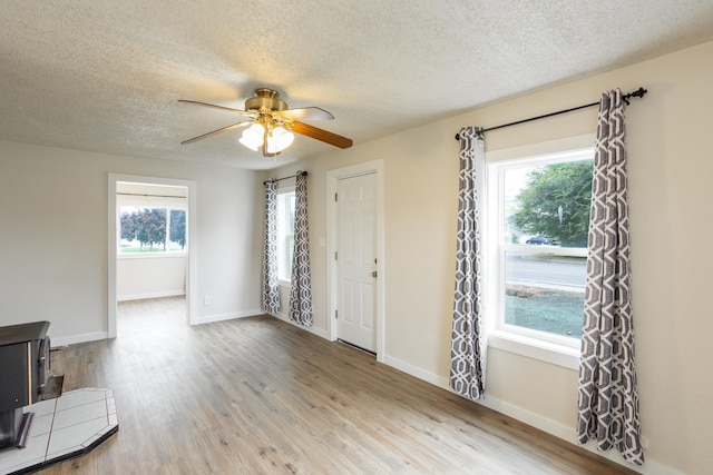 unfurnished living room featuring hardwood / wood-style floors, a textured ceiling, ceiling fan, and a healthy amount of sunlight