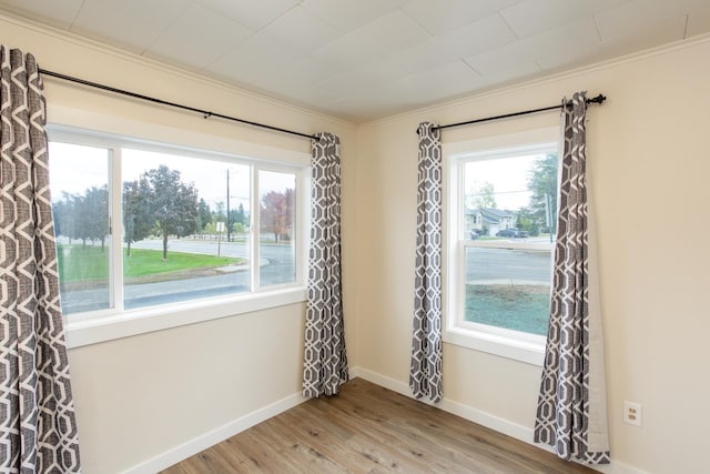 unfurnished room featuring plenty of natural light, wood-type flooring, and ornamental molding