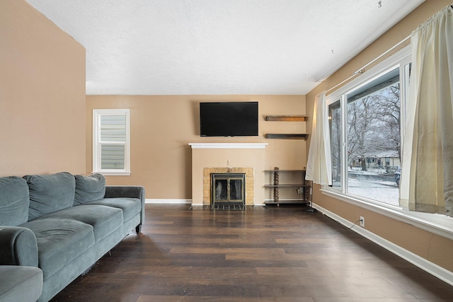 living room with a textured ceiling, plenty of natural light, a fireplace, and dark wood-type flooring