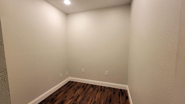 empty room with dark wood-type flooring and baseboards