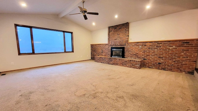 unfurnished living room with a ceiling fan, carpet, brick wall, a brick fireplace, and vaulted ceiling with beams