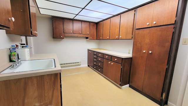 kitchen featuring light countertops, baseboard heating, and a sink