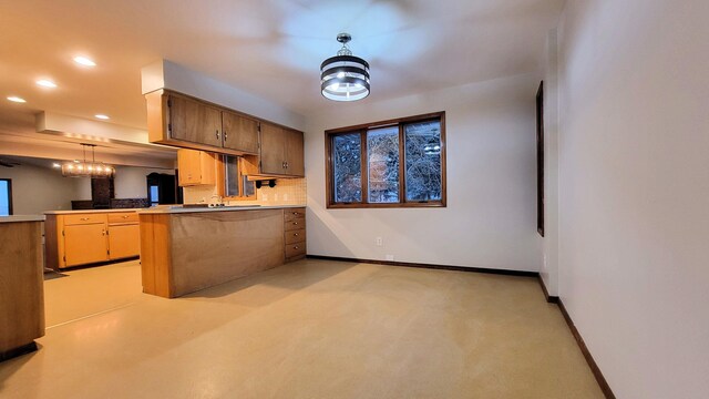 kitchen with baseboards, a peninsula, recessed lighting, hanging light fixtures, and light countertops