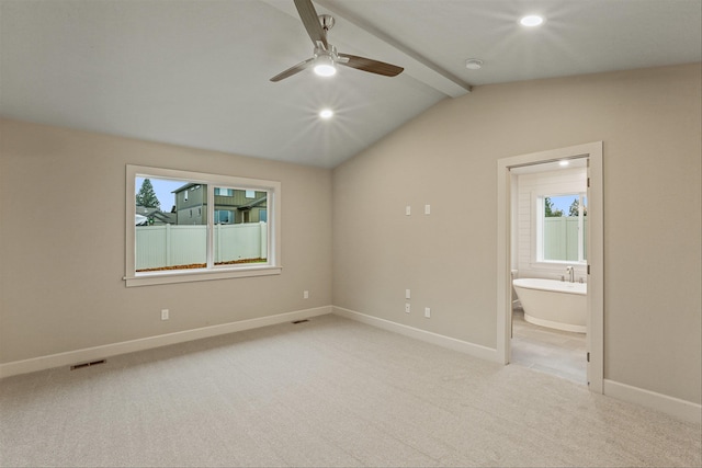 unfurnished bedroom featuring connected bathroom, multiple windows, ceiling fan, and lofted ceiling with beams