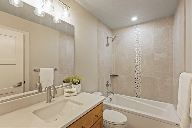 full bathroom with a textured ceiling, vanity, toilet, and tiled shower / bath