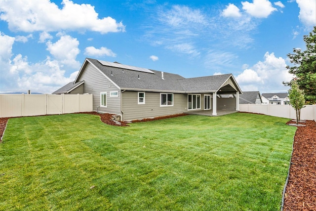 back of property featuring a lawn, a patio, and solar panels