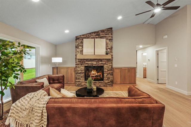 living room with ceiling fan, light hardwood / wood-style floors, lofted ceiling, and a fireplace