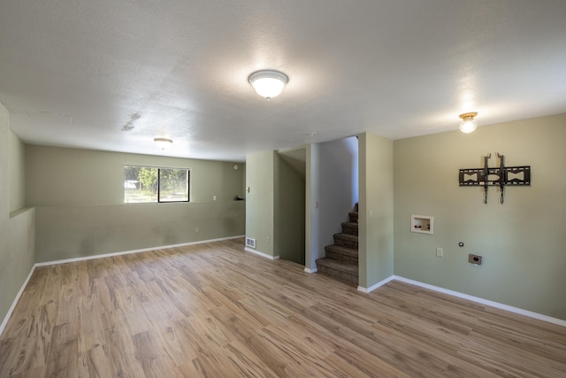 basement with a textured ceiling and light hardwood / wood-style flooring