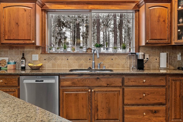 kitchen featuring sink, stainless steel dishwasher, tasteful backsplash, and dark stone countertops