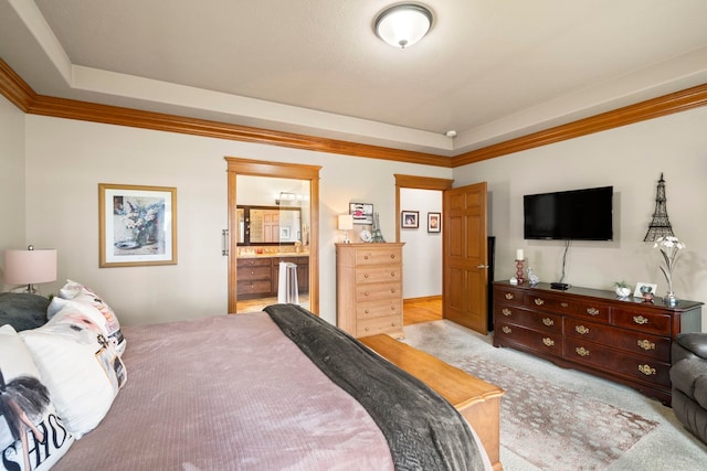 bedroom with light colored carpet, crown molding, a tray ceiling, and ensuite bath