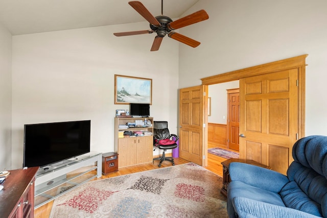 living room with ceiling fan, light hardwood / wood-style flooring, and vaulted ceiling