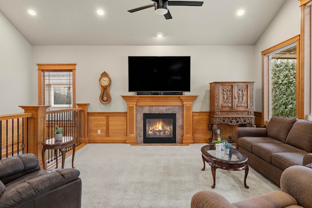 carpeted living room with ceiling fan, lofted ceiling, wood walls, and a fireplace