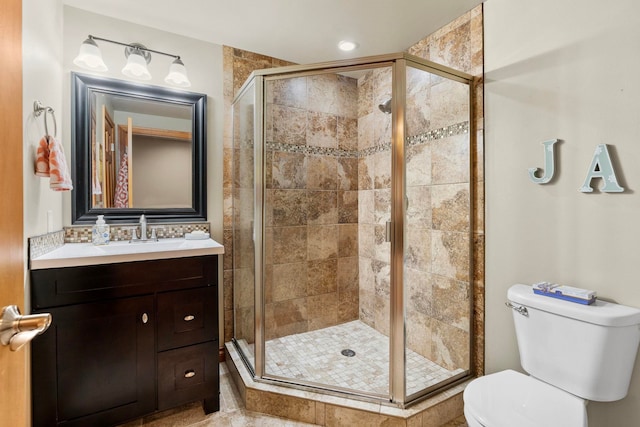 bathroom with toilet, vanity, and a shower with shower door