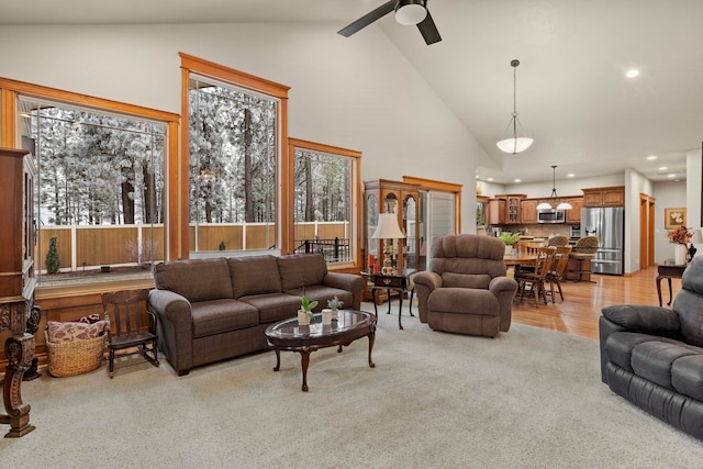 carpeted living room with ceiling fan and high vaulted ceiling