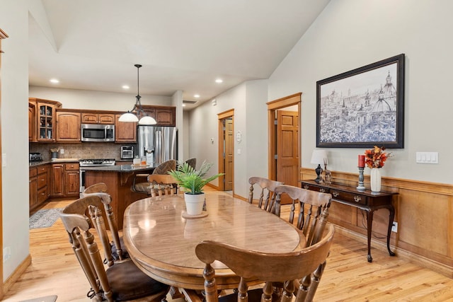 dining room with light hardwood / wood-style floors and vaulted ceiling