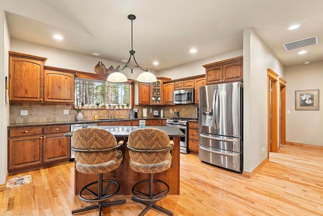 kitchen featuring a breakfast bar area, stainless steel appliances, decorative backsplash, a center island, and sink