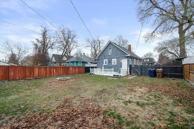 rear view of property with a deck, an outdoor fire pit, and a lawn