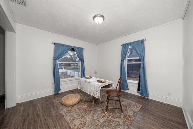 dining room featuring ornamental molding, a textured ceiling, and dark wood-type flooring