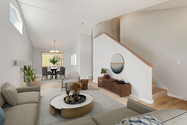 living room featuring an inviting chandelier, lofted ceiling, and light hardwood / wood-style flooring