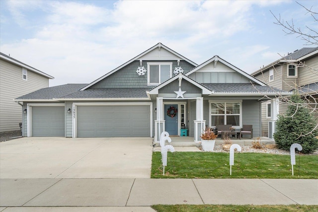 view of front of home featuring a front lawn, covered porch, and a garage