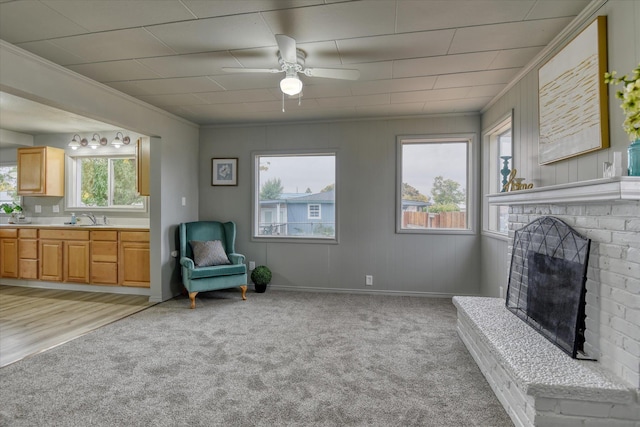 living area with a brick fireplace, ornamental molding, sink, and light hardwood / wood-style flooring