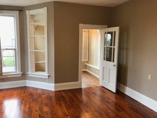 unfurnished room with dark hardwood / wood-style flooring and a textured ceiling