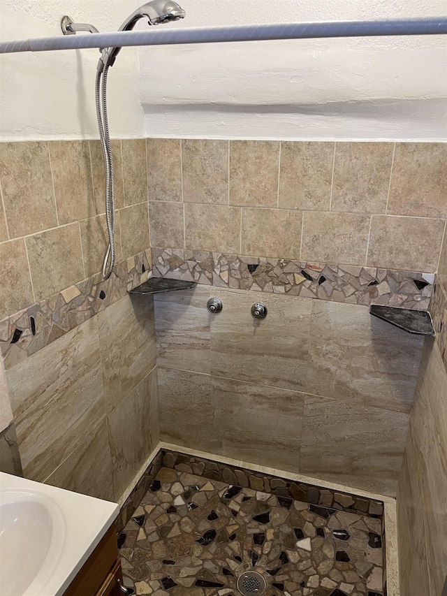 bathroom featuring a tile shower and vanity