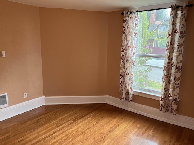 empty room with a wealth of natural light and hardwood / wood-style flooring