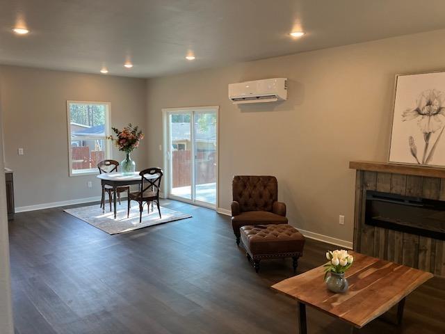 38105 N Frontage Rd, Elk, WA 99009 - living room with an AC wall unit, dark wood-style flooring, a fireplace, and recessed lighting