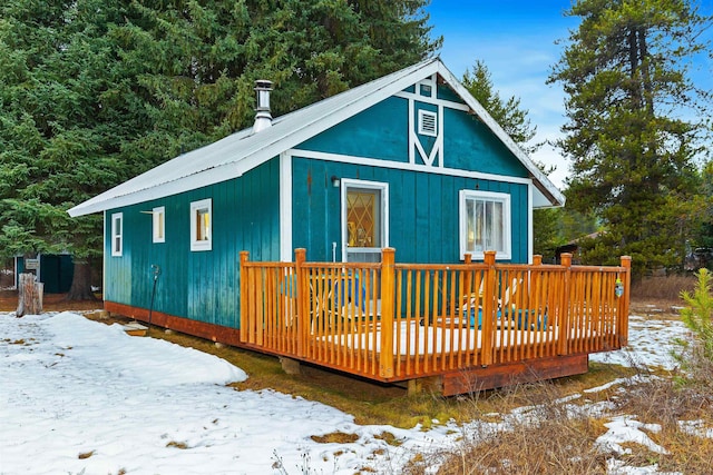 snow covered back of property with a deck