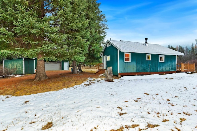 view of snowy exterior featuring an outbuilding and a garage