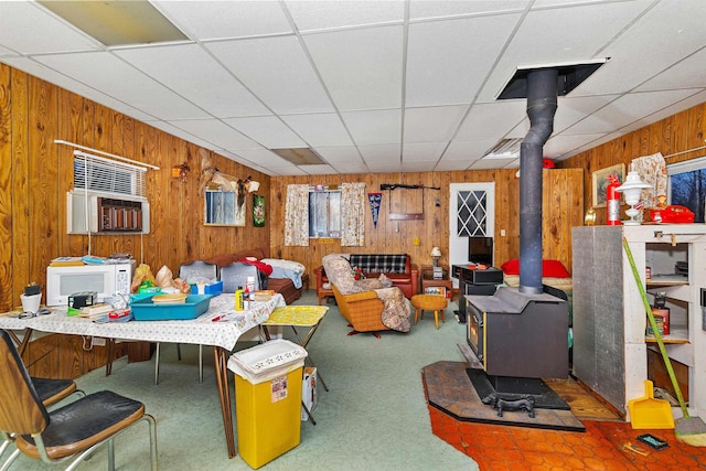 interior space with a wood stove, wood walls, and a paneled ceiling