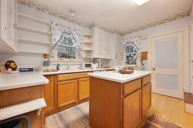 kitchen featuring pendant lighting, light wood-type flooring, a center island, and sink