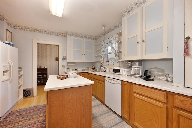 kitchen featuring sink, a kitchen island, white appliances, white cabinets, and light wood-type flooring