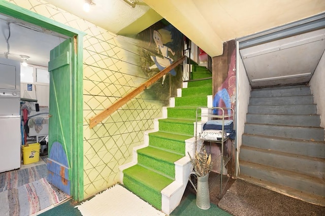 stairs featuring stacked washer and dryer