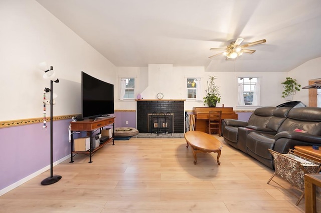 living room with light hardwood / wood-style floors, a wood stove, and ceiling fan