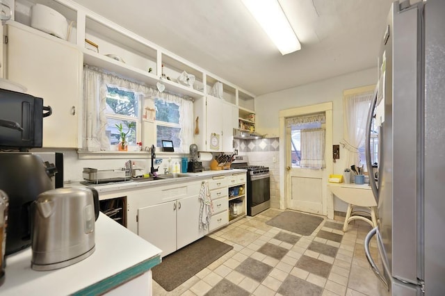 kitchen with light tile patterned flooring, sink, white cabinets, and stainless steel appliances