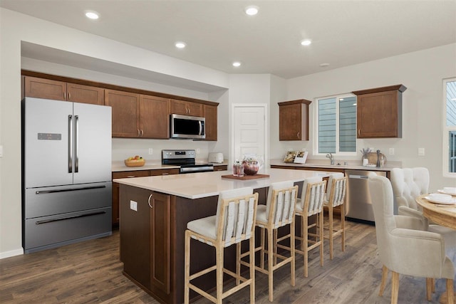 kitchen featuring a kitchen bar, stainless steel appliances, dark wood-type flooring, sink, and a center island