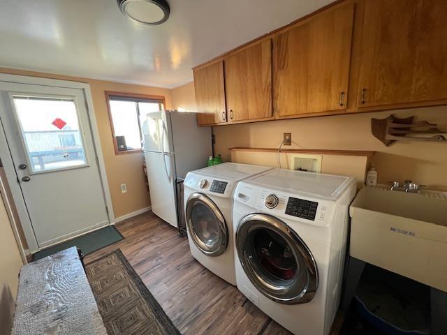 laundry area featuring separate washer and dryer, cabinets, sink, and wood-type flooring